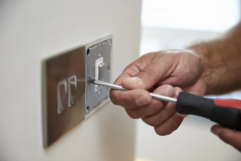 Architecte ou ing&eacute;nieur en chemise &agrave; carreaux travaillant sur des plans techniques dans un bureau lumineux avec grande fen&ecirc;tre donnant sur verdure